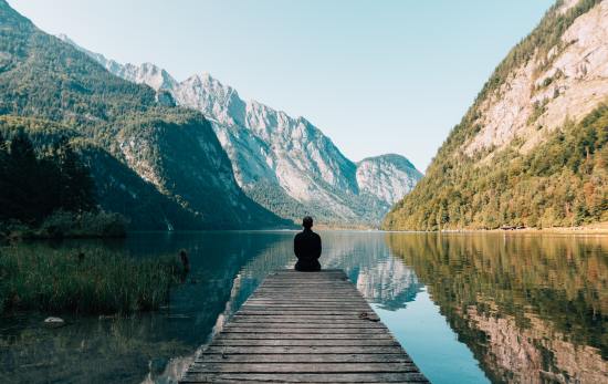 man sitting and meditation in front of a lake trying to understand "what is meditation?"